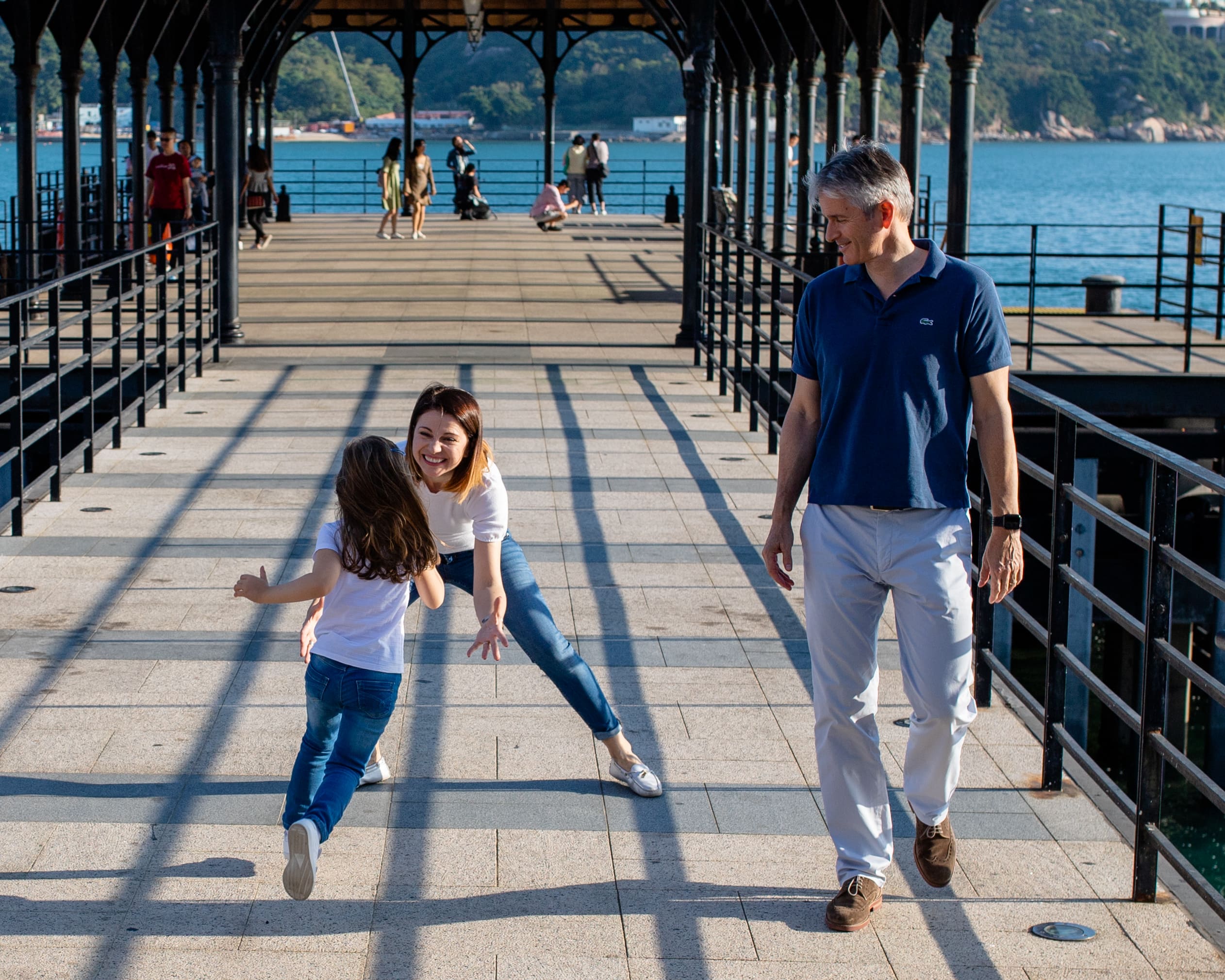 daughter running into moms arms while dad smiles looking on.  photo taken on Blake pier in Stanley Hong Kong
