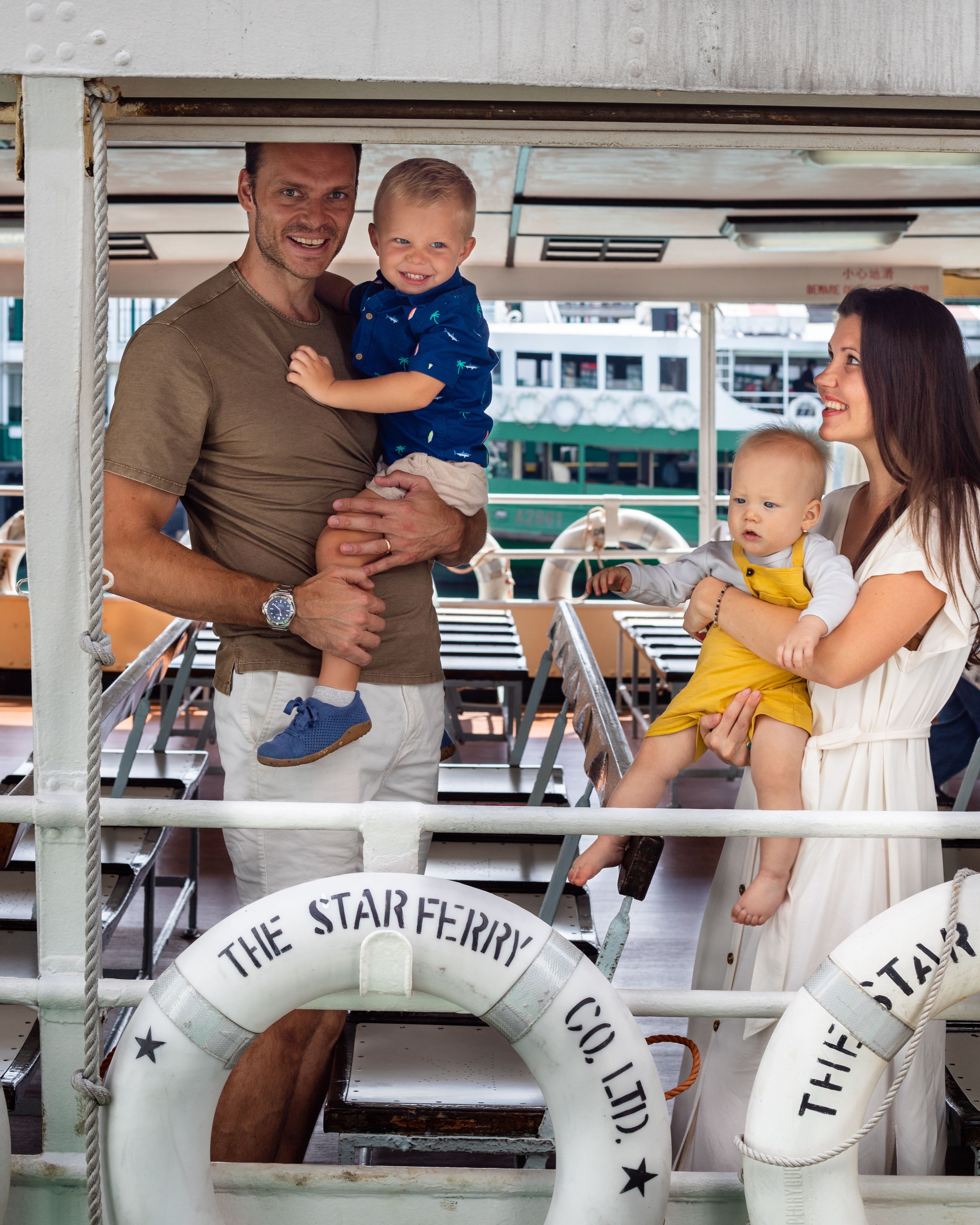 A mom and dad taking their two young boys for a ride on the Hong Kong Star Ferry 