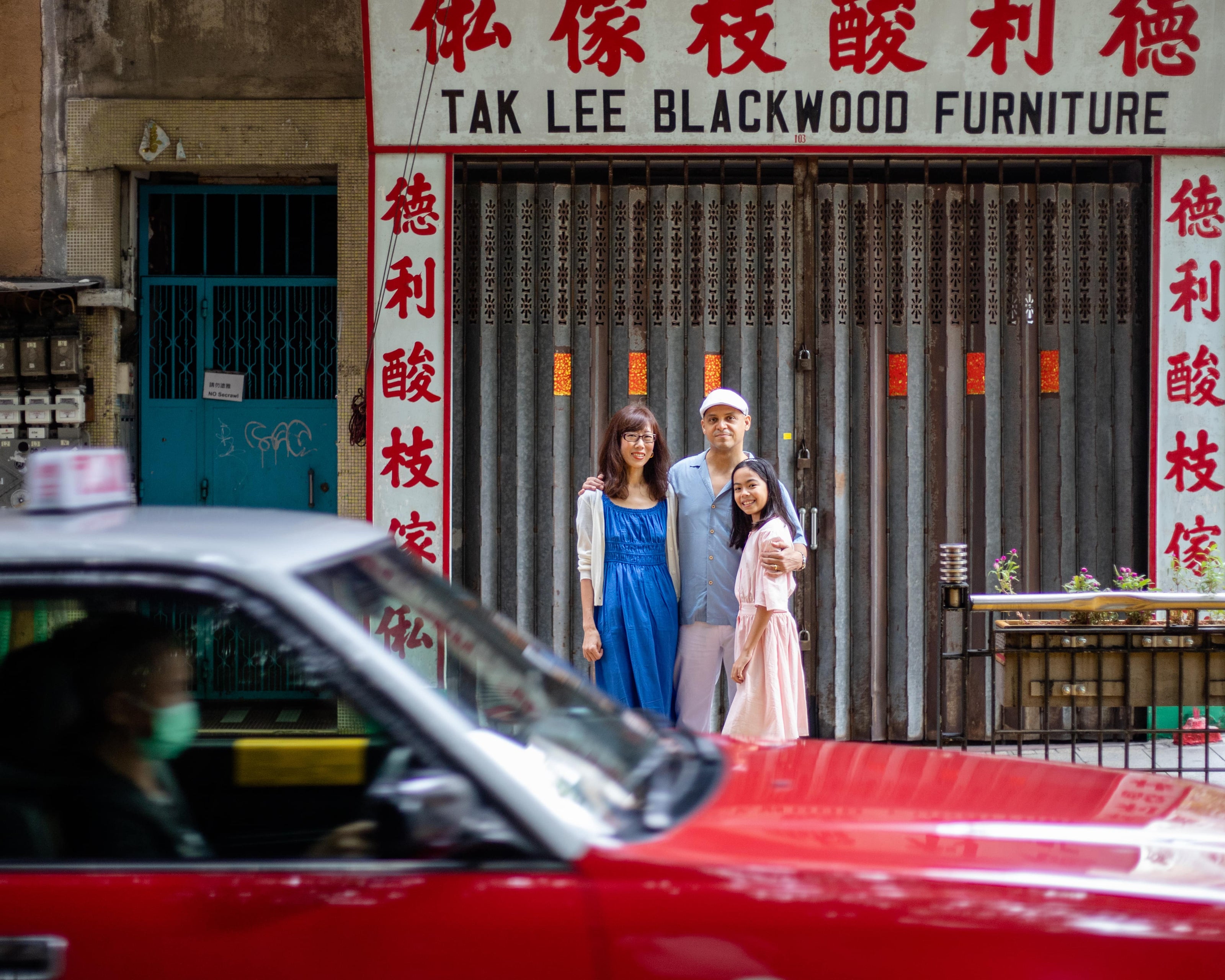 a family of 3 with a red hong kong taxi 